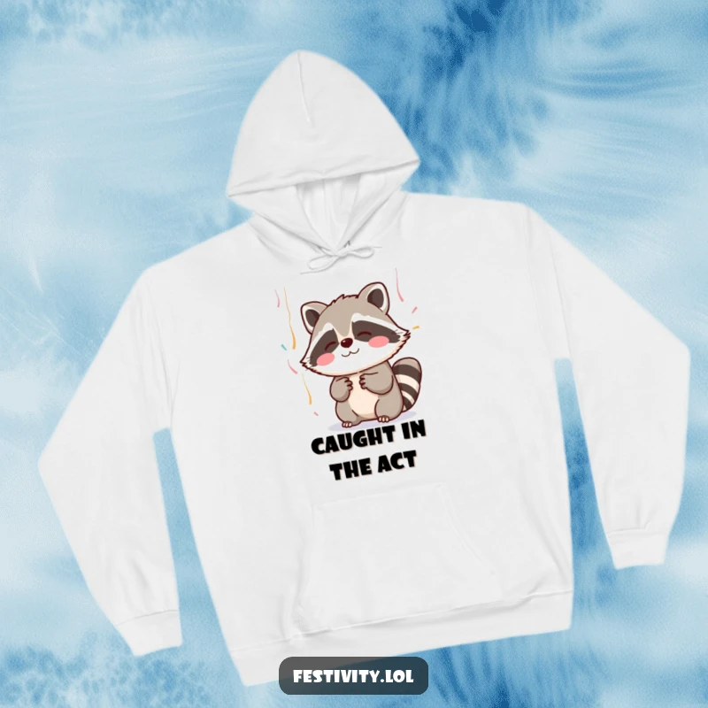 Funny hoodie featuring a blushing raccoon adorably reaching for falling streamers, offering cozy and cute vibes.