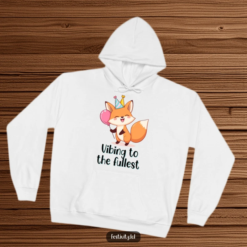 Funny hoodie with a giggling fox in a party hat bouncing a large balloon, ideal for cozy, cheerful, and humorous occasions.